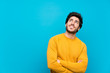 © luismolinero - Handsome over isolated blue wall looking up while smiling
