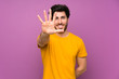 © luismolinero - Handsome over isolated purple wall counting five with fingers