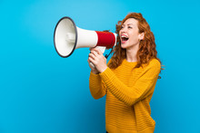 Redhead Woman With Yellow Sweater Shouting Through A Megaphone