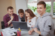 © Ihor - Cheerful teenage boy smiling to the camera, his classmates working on a project with teacher on the background. Happy teen male student enjoying studying at high school
