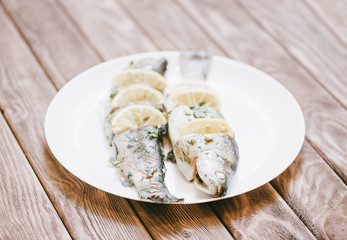 Wall Mural - Fish trout dish with lemons on a white plate.