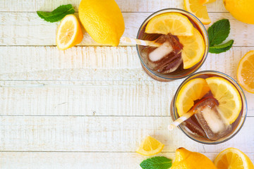 Sweet summer iced tea. Top view corner border with copy space on a white wood background.