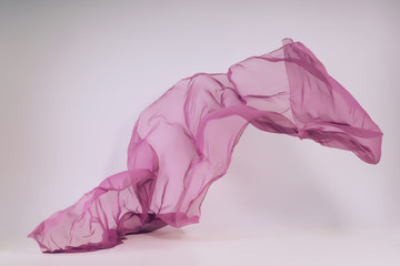 Purple fabric on a white background. Levitation of ultraviolet tissue in the photo studio. A soaring piece of cotton fabric. Flying colored fabric on a light background