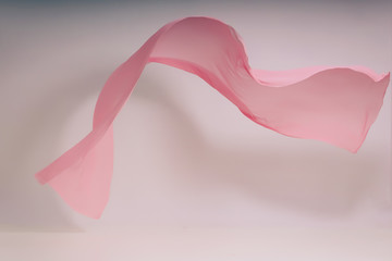 Pink fabric on a white background. Pink fabric levitation in photo studio. A soaring piece of cotton fabric. Flying colored fabric on a light background