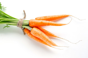 Wall Mural - Fresh carrots with green foliage on white background.