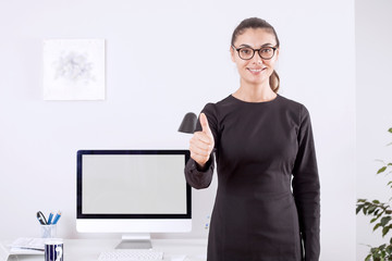 beautiful young businesswoman standing with crossed arms and smiling at camera in office