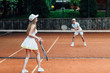 © Тарас Нагирняк - Two fit woman in cap and tennis uniform serving tennis ball during training on the outdoor tennis court.