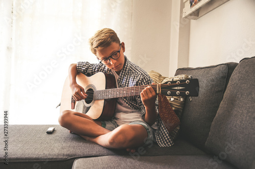 Beautiful Young Boy Playing Acoustic Guitar Music Student Exercises Alone At Home Trendy Caucasian Child Plays Instruments Sitting Legs Crossed On The Sofa Blonde Guy Doing Musical Homework Stock Photo Adobe