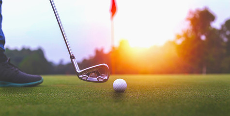 Golf balls and golf club on green grass shiny light sunse