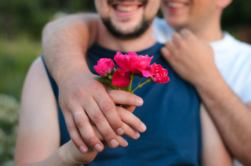 close up of happy male gay couple with red rose flower holding hands. lgbt, homosexuality, same-sex marriage and love concep