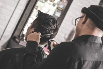 Wall Mural - rear view of barber man cutting his male costumer in barbershop