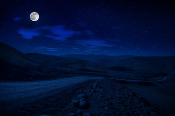 Wall Mural - mountain road through the forest on a full moon night. scenic night landscape of country road at nig