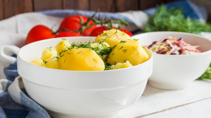 boiled potato with dill in bowl and fresh salad close up