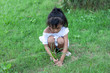 © Pannarai - A girl help gardening by sitting pull out weeds in lawn.