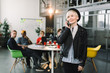© sofiko14 - Caucasian pretty business woman in hat and jacket using phone. successful European business woman, talking on the phone, standing on background of colleagues on meeting in modern loft office