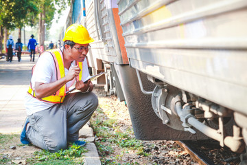 The young engineer is working on the train. He is recording the operation information of the machine.