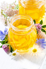 Wall Mural - jars with fresh flower honey on white wooden board, vertical closeup