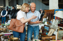 Mature Man And His Wife Are Visiting Market Of Old Things