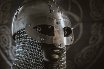 Viking helmet with chain mail of iron on red shield of wood and golden triskel