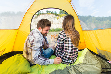 people, summer tourism and nature concept - young couple resting in camping tent, view from inside