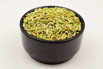 Wall Mural - fennel seeds in black bowl isolated on white background.