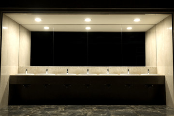 Public toilet and bathroom interior with wash basin..Faucets with of washbasins in public toilet room..Modern sinks with mirror