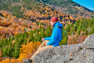 Wall Mural - Backpacker man hiking at Artist's Bluff in autumn. Fall colours in Franconia Notch State Park. White Mountain National Forest, New Hampshire, USA