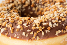 Macro Sweet Photo Of Chocolate Donut. Texture Donut With Pieces Of Nuts Closeup