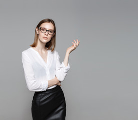 Portrait of the young modern business woman. The strict beautiful thin brunette with the equal business leader of the woman of hair in casual clothes. Gray background.