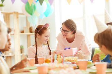 Wall Mural - Portrait of smiling mother giving Birthday present to daughter during party, copy space