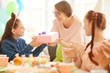 © Seventyfour - Portrait of happy girl  receiving gift from mom during Birthday party with friends, copy space