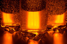 Bottom Of Three Glass Cups With Liquid And Bubbles On Orange Background Close Up On Table