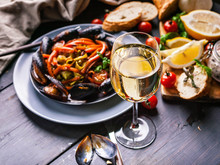 A Glass Of Dry White Wine On The Background Of Italian Cuisine. Pasta, Mussels And Wine.