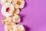 Fototapeta Tulipany - Dried apple chips over purple background with copy space.