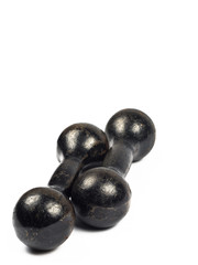 Two vintage cast iron black dumbbells stacked in parallel, on a white background