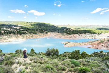 Beautiful Spanish mountain landscape with a lake, a man in a white straw hat with a camera. Travel and vacation concept.