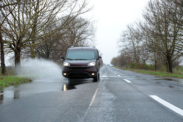 Wall Mural - Wet suburban road with car on rainy day