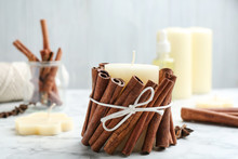 Candle With Cinnamon Sticks On Marble Table