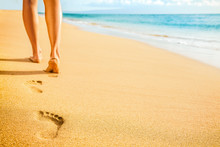 Beach Woman Legs Feet Walking Barefoot On Sand Leaving Footprints On Golden Sand In Sunset. Vacation Travel Freedom People Relaxing In Summer.
