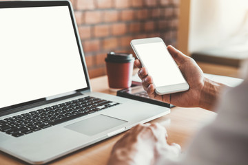 Businesss man using laptop and Mobile Phone with blank screen in the office.