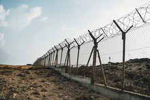 Barbed Wire Steel Wall Against The Immigations. Wall With Barbed Wire On The Border Of 2 Countries. Private Or Closed Military Zone.