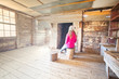 © Leah-Anne Thompson - Woman sitting inside an old timber hut on log stools Snowy Mountains