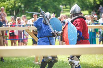 medieval jousting knight fight, in armor, helmets, chain mail with axes and swords on lists. historic reconstruction of ancient fight