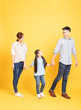 © Tom Wang - Full length portrait of happy family walking over yellow background