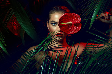 Wall Mural - a beautiful tanned girl with natural make-up and wet hair stands in the jungle among exotic plants.