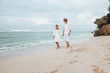 © Smeilov - girl and a man in white clothes walk on a white beach and hold hands