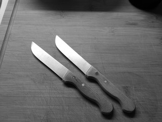 Two knives over a wooden cutting board