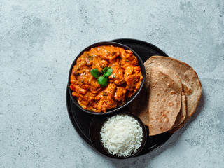 Indian cuisine dishes: tikka masala, rice, samosa, chapati,. Indian food on gray stone background with copy space. Assortment indian meal top view or flat lay.