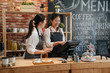 © PR Image Factory - asian female barista telling something funny to colleague while working. two young girls coffeehouse staff laughing together and chatting gossip in modern coffee store. customer meal on bar counter