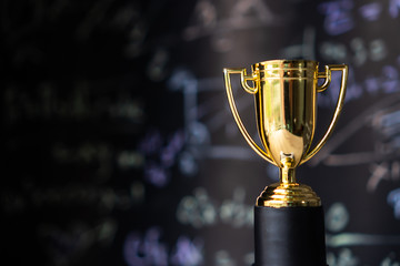 achievement success in education awards concept: golden trophy cup winner on blur formula equation b